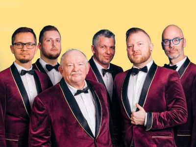 The Bromantics band publicity shot: six men wearing dark red velvet tuxedos.
