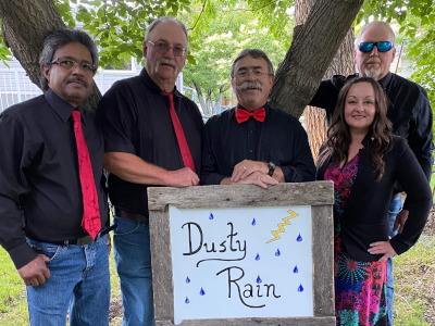 Dusty Rain band: four men and a woman wearing black holding a sign saying "Dusty Rain."